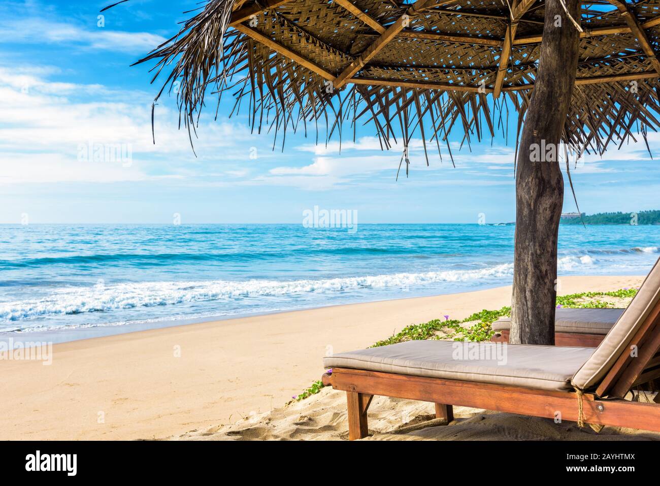 Lit de plage avec parasol sur la belle plage tropicale Banque D'Images