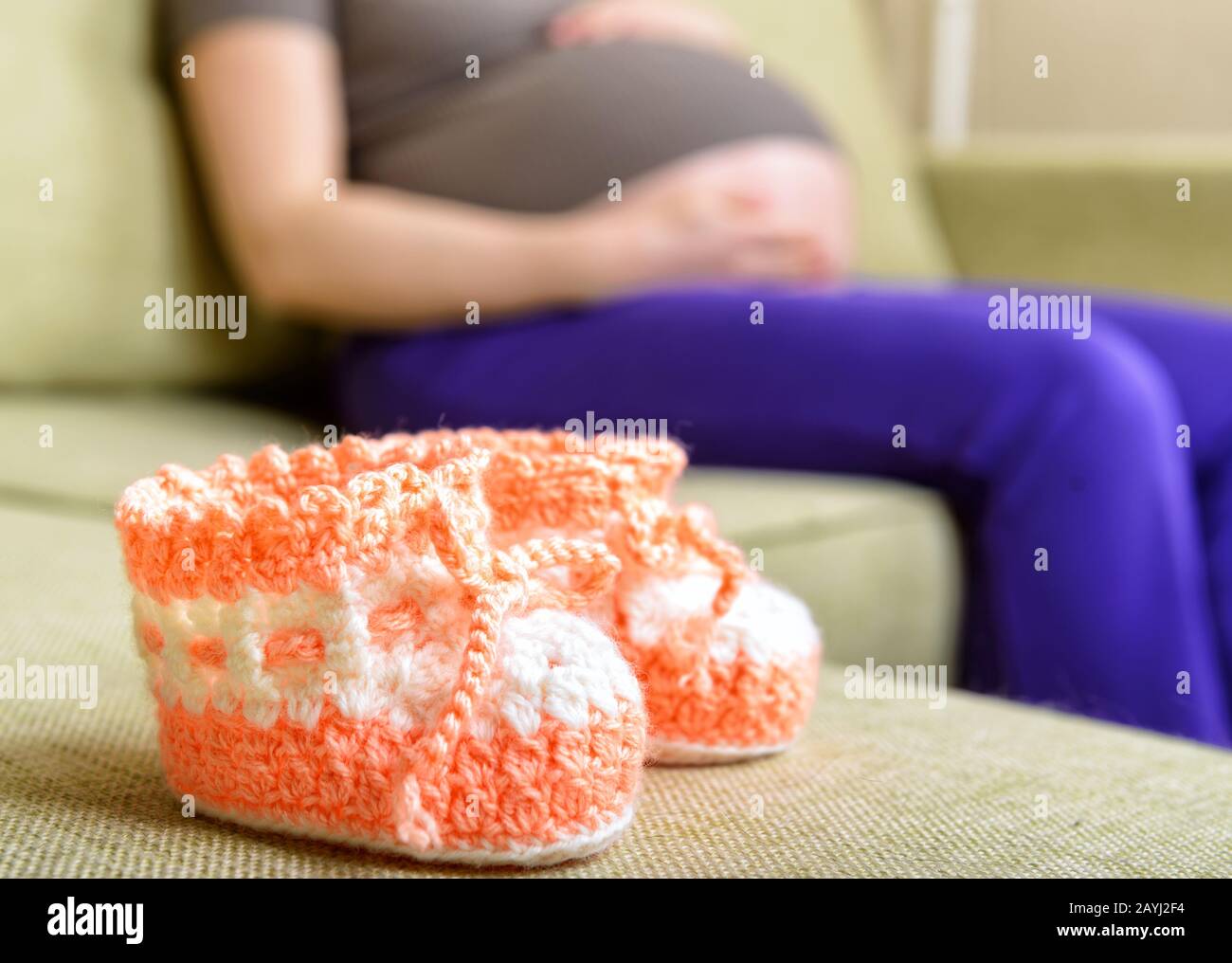 Une belle chaussures de bébé en laine sur le canapé à côté d'une femme enceinte Banque D'Images Une belle chaussures de bébé en laine sur le canapé à côté d'une femme enceinte Banque D'Images