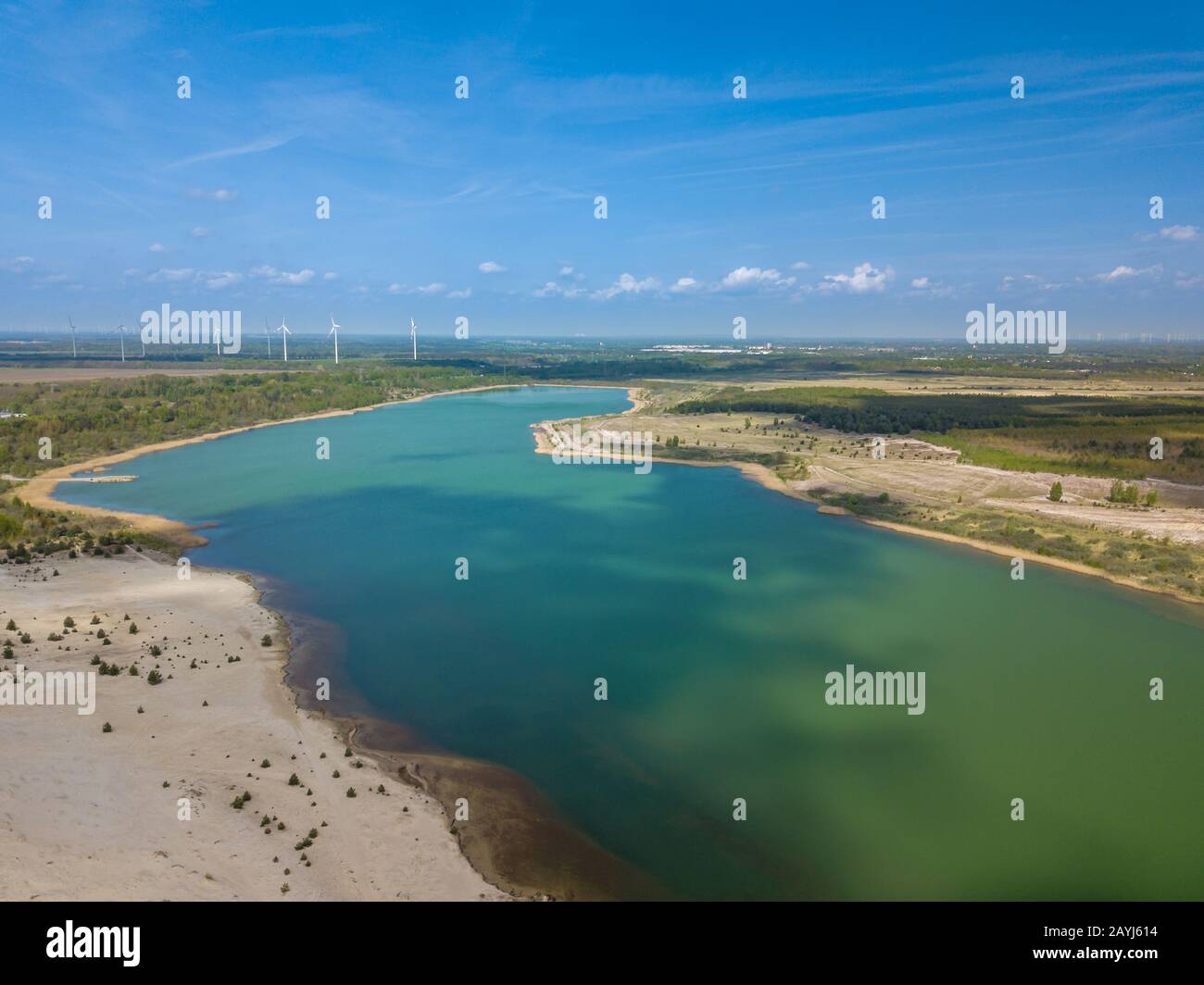 Roues de vent pour l'énergie verte dans le fond d'un lac de couleur torquiose. Banque D'Images