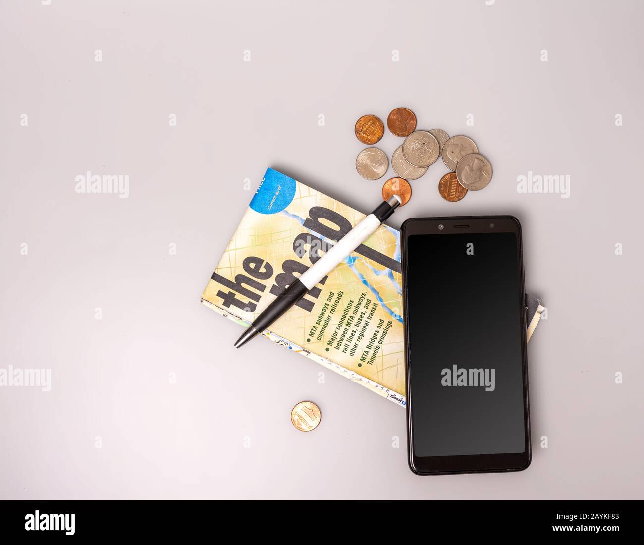 Téléphone, argent, stylo et carte pliée sur fond gris. Vue de dessus. Gros plan. Banque D'Images
