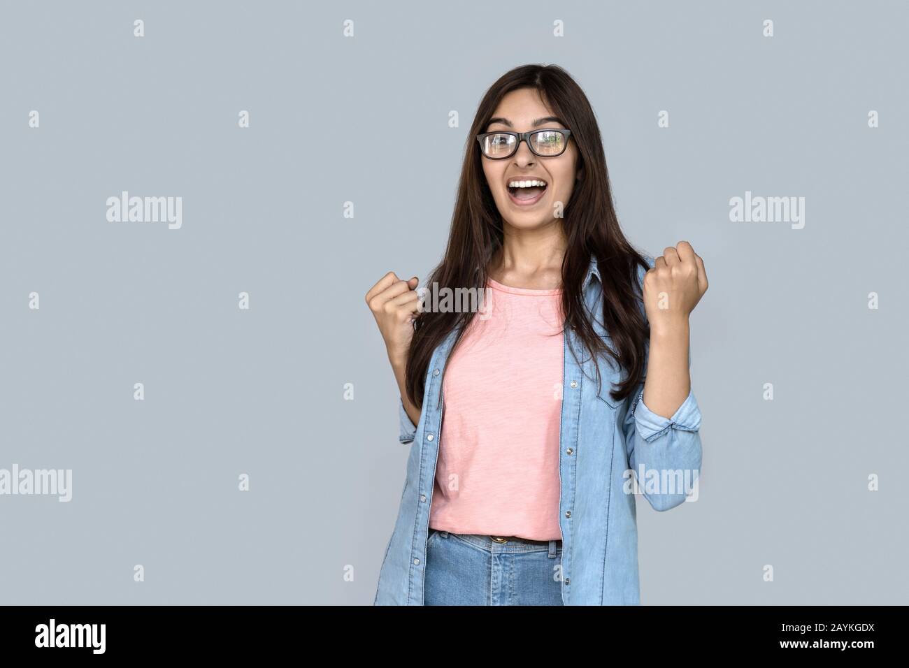 La jeune fille indienne excitée gagnante célèbre le succès isolé sur fond gris Banque D'Images