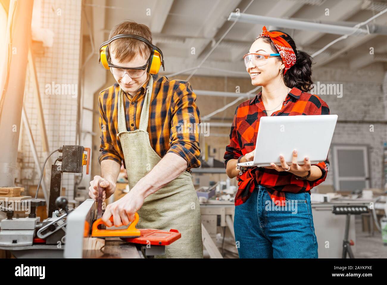 Femme asiatique avec un ordinateur portable et un homme avec une scie circulaire travaillant dans une usine ou un atelier Banque D'Images
