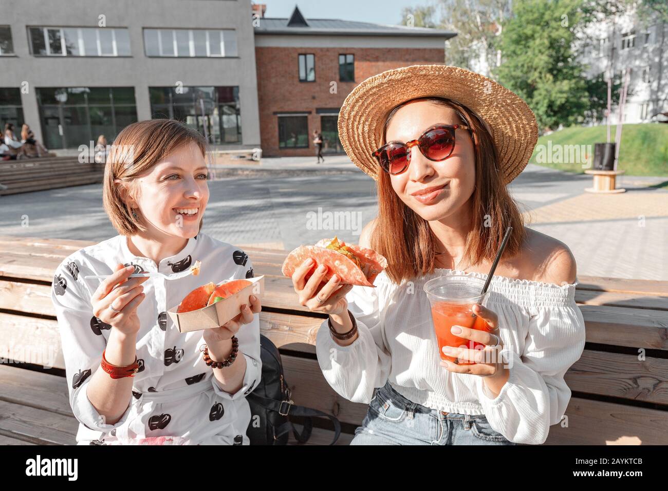 Deux filles mangent des tacos traditionnels mexicains de la restauration rapide et boivent michelada dans la rue. Concept de communication et de plats à emporter Banque D'Images