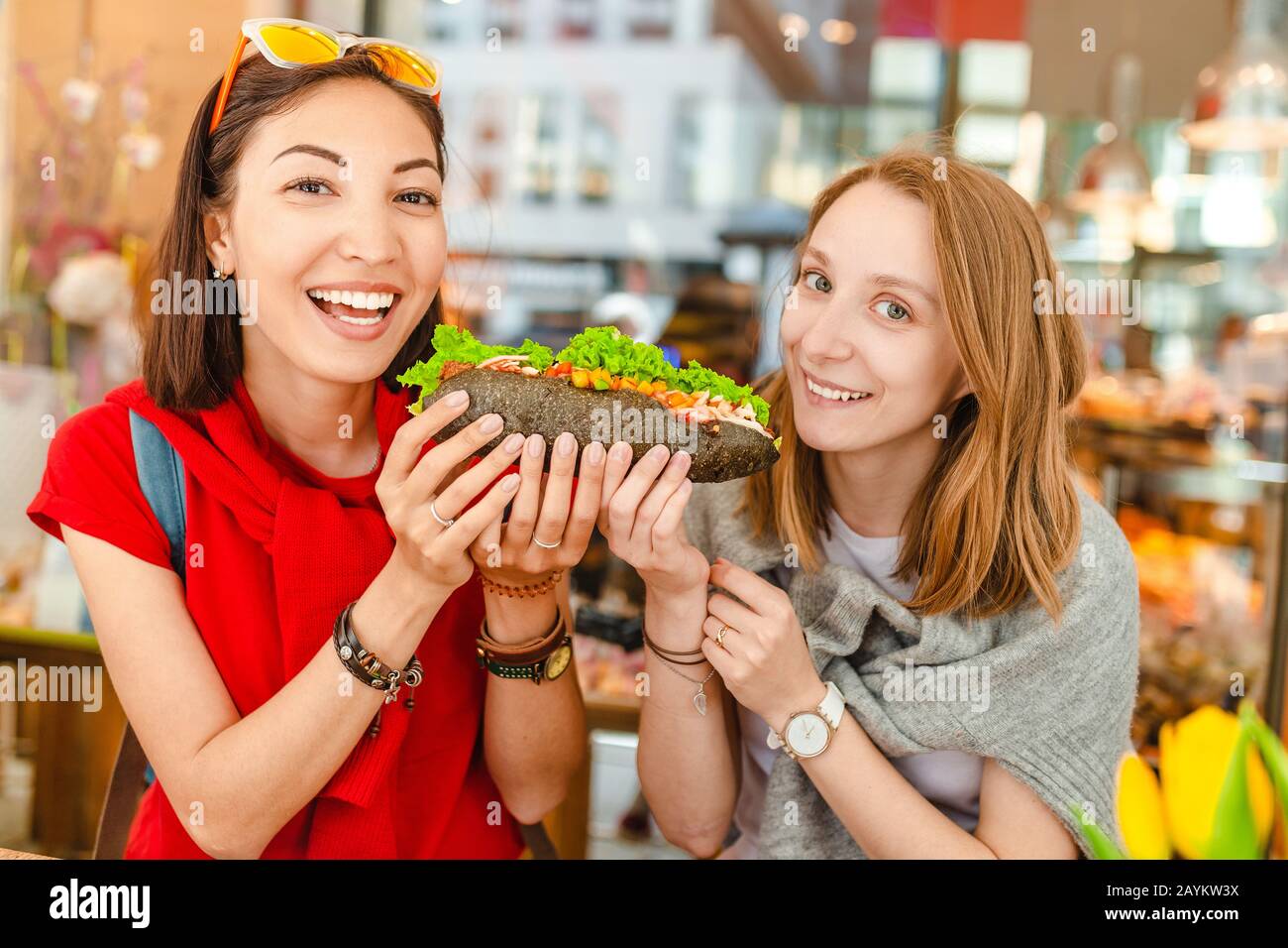 Des amis multiraciaux et gaies mangeant un sandwich et s'amuser dans un café Banque D'Images
