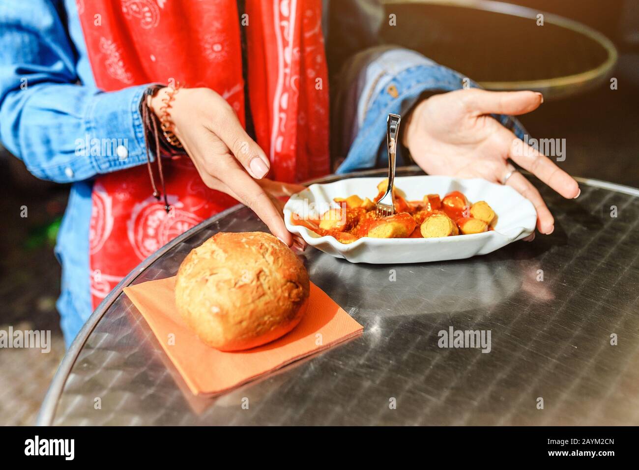 Femme mangeant Currywurst avec du pain dans le café de la rue de Berlin. Concept de cuisine locale allemande Banque D'Images