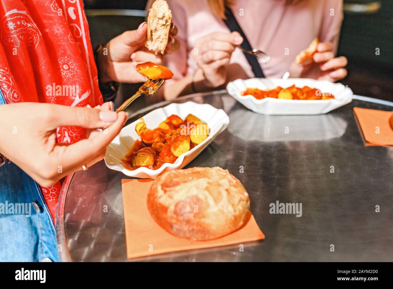 Femme mangeant Currywurst avec du pain dans le café de la rue de Berlin. Concept de cuisine locale allemande Banque D'Images