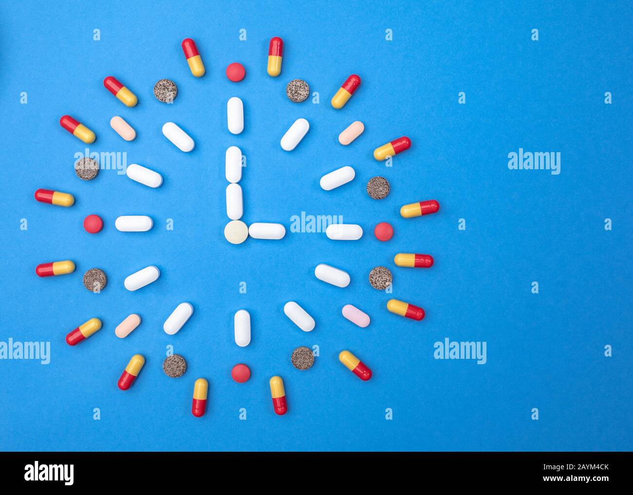 Différents types de pilules disposés en forme d'horloge sur fond bleu. Concept de pharmacie et de médecine Banque D'Images