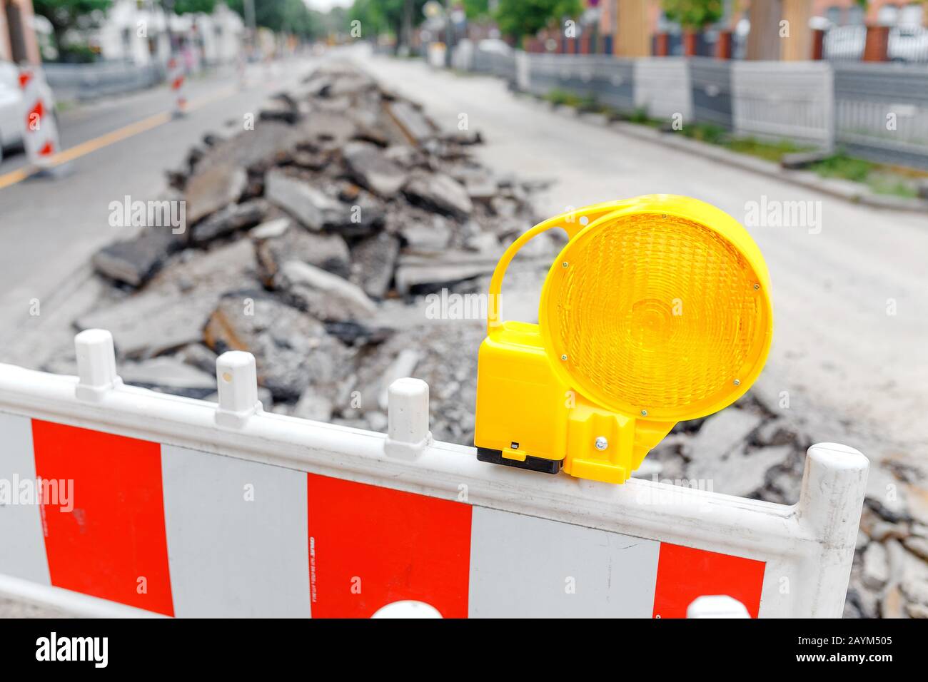 Gros plan sur une clôture avec une lampe jaune sur une rue fermée pour la réparation d'un asphalte sur une route urbaine Banque D'Images