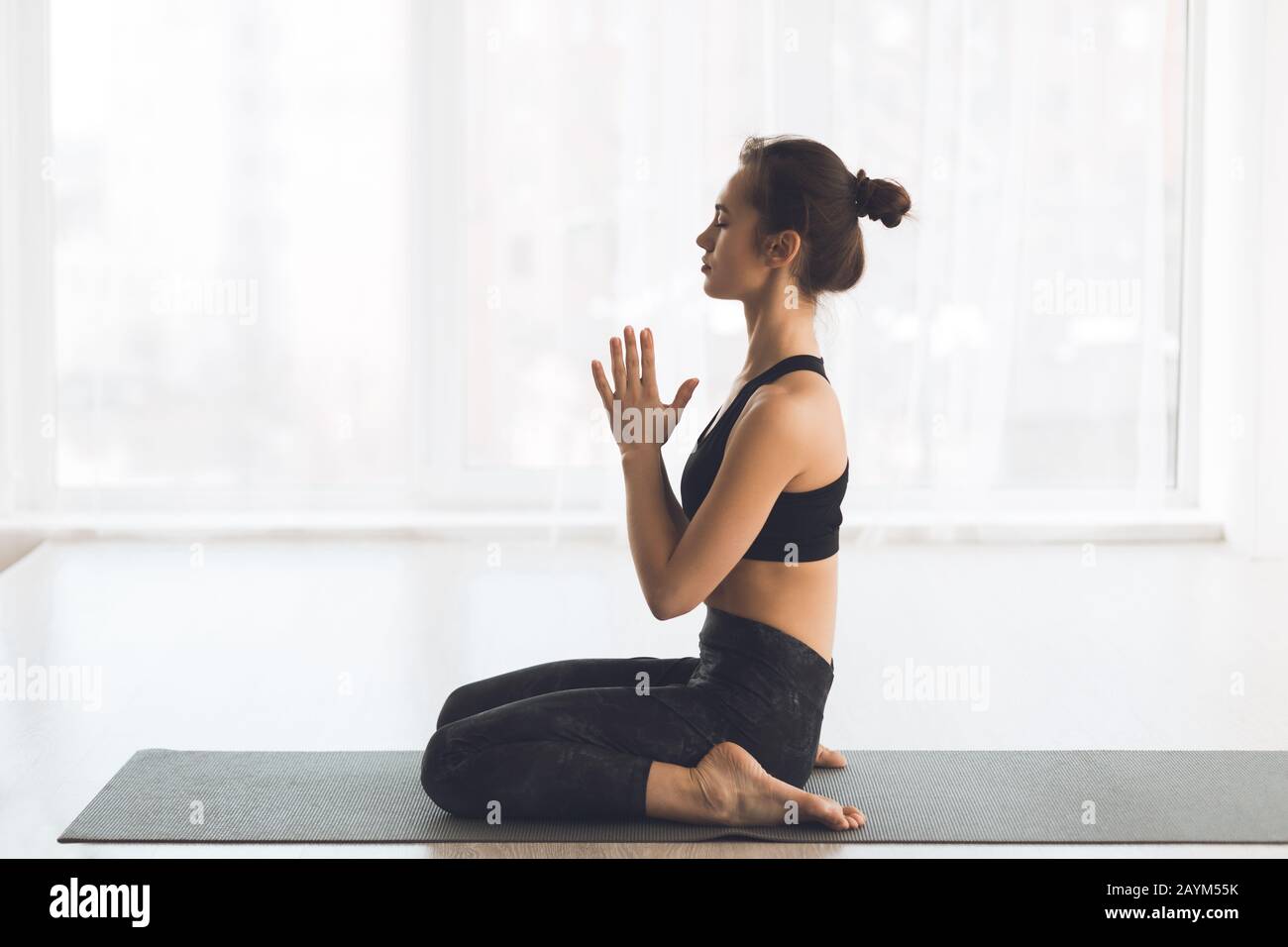 Vue latérale de la femme yogi faisant un geste namaste à la maison Banque D'Images