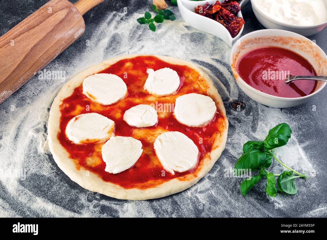 Pâte à pizza bouchées pour la cuisson avec sauce tomate, basilic et autres ingrédients. Banque D'Images