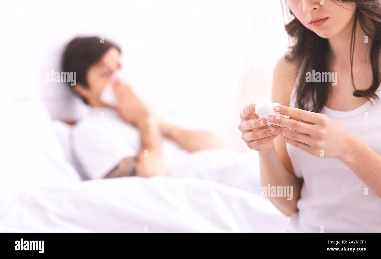 Jeune femme lisant l'instruction de médicaments pour son mari malade Banque D'Images