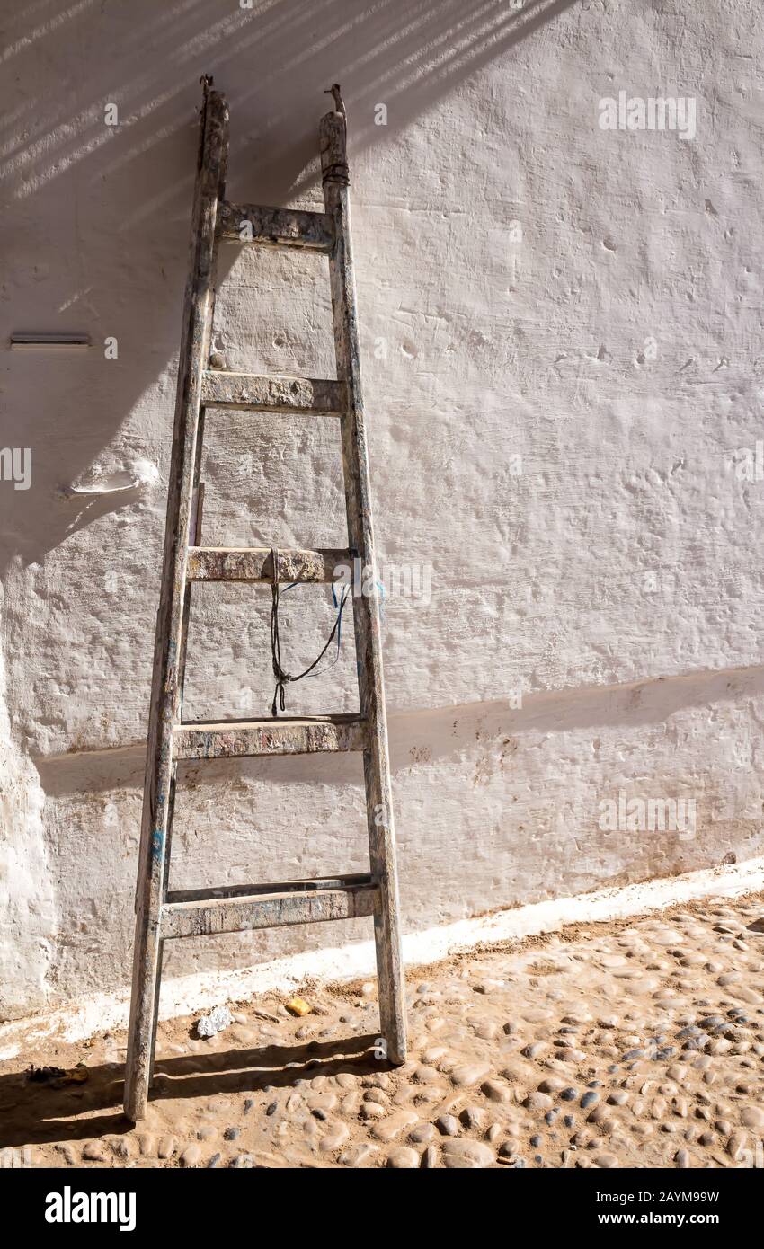 Mur structuré blanc avec une ancienne échelle en bois sur pied. Rue D'Essaouira, Maroc. Banque D'Images