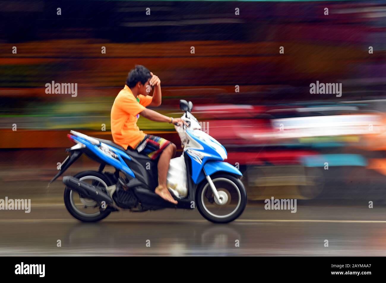 Motocycliste protégeant les yeux de la main contre la pluie, Thaïlande, Phuket Banque D'Images