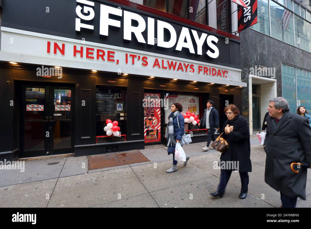 Les gens qui marchont devant un TGI Fridays Happy Hour Themed chain restaurant au 604 5ème Avenue à Midtown Manhattan, New York, NY. Banque D'Images