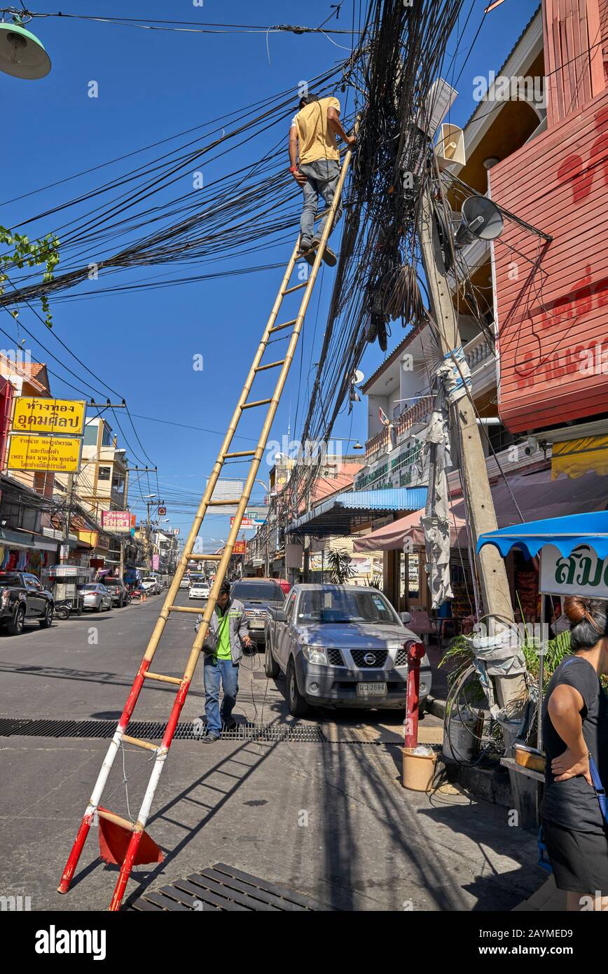 Lineman travaille au-dessus de la tête parmi une myriade de fils et de câbles électriques. Thaïlande S. E. Asie Banque D'Images
