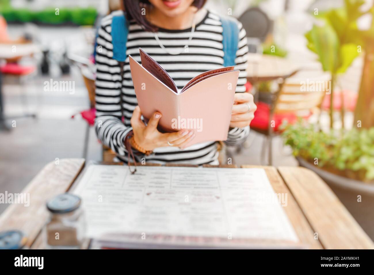 Jeune femme de voyage belle dans la lecture du menu et de faire une commande sur la terrasse du café, concept de cuisine locale Banque D'Images