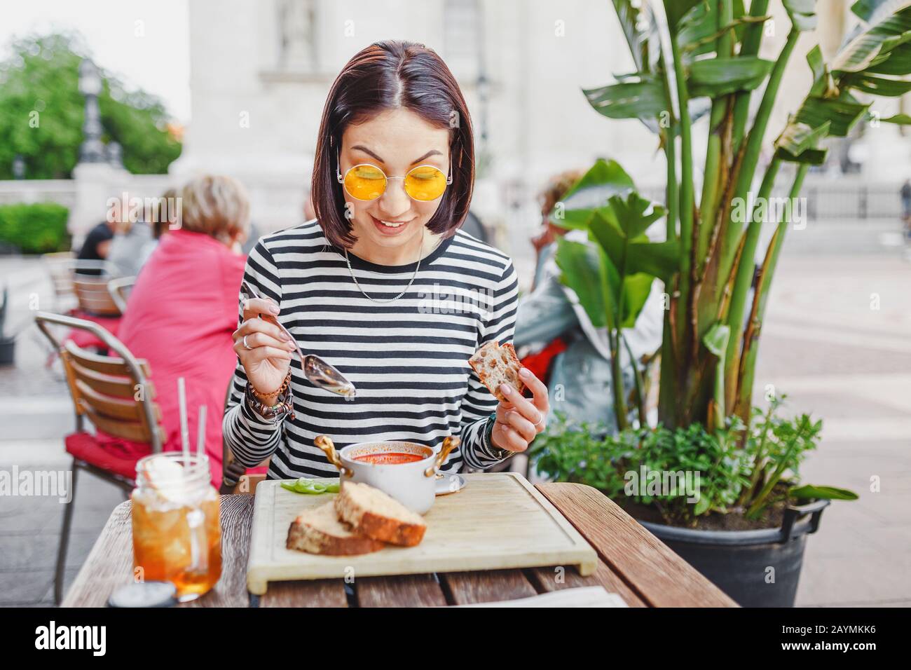 Jolie fille hipster mangeant de la soupe goulash au restaurant extérieur, cuisine locale et concept de déjeuner Banque D'Images