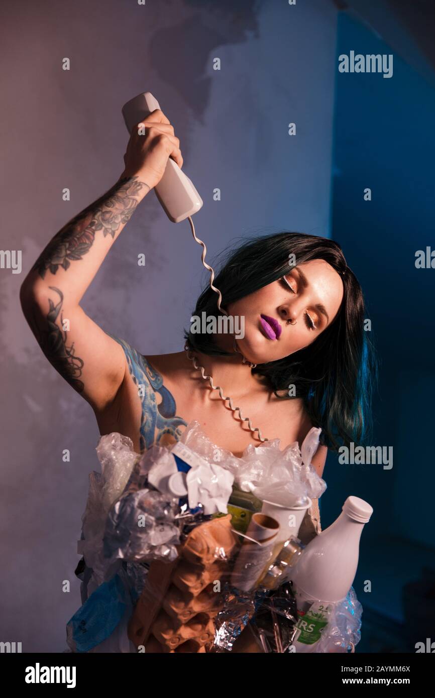 Étranglé PAR UN FIL TÉLÉPHONIQUE: Portrait d'une femelle souriante écofighter portant une robe à ordures en plastique et en carton pour aider à répandre le nettoyage de l'environnement Banque D'Images