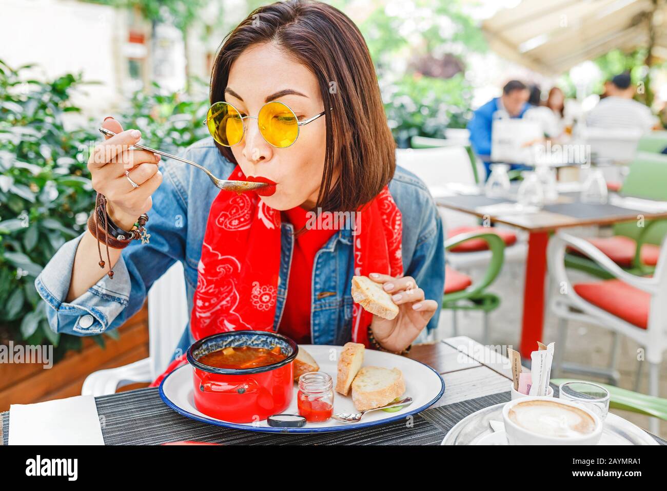 Une jeune fille asiatique qui mange de la soupe de goulash hongroise dans une casserole rouge décorative au restaurant extérieur Banque D'Images