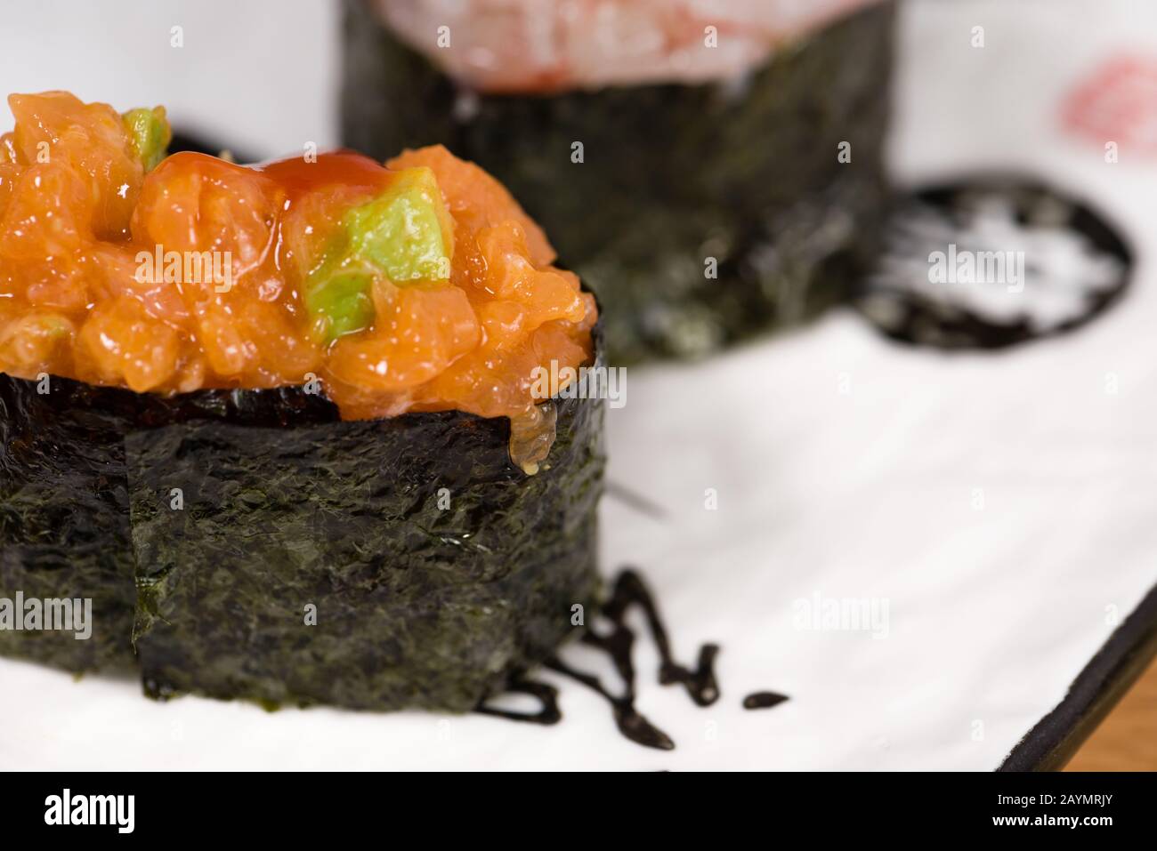 gunkan avec tartare de saumon et d'avocat enveloppé dans de l'algue nori servie sur une plaque rectangulaire Banque D'Images