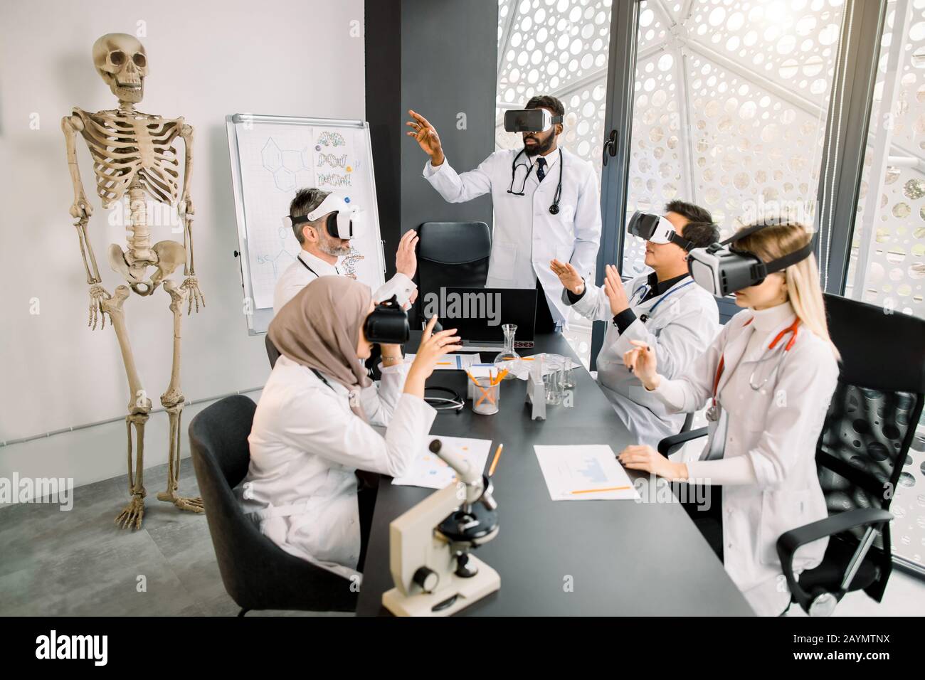 Groupe d'étudiants multiethniques avec professeur apprennent la médecine ou le projet scientifique avec des lunettes vr en laboratoire moderne. Recherche médicale, chimie Banque D'Images