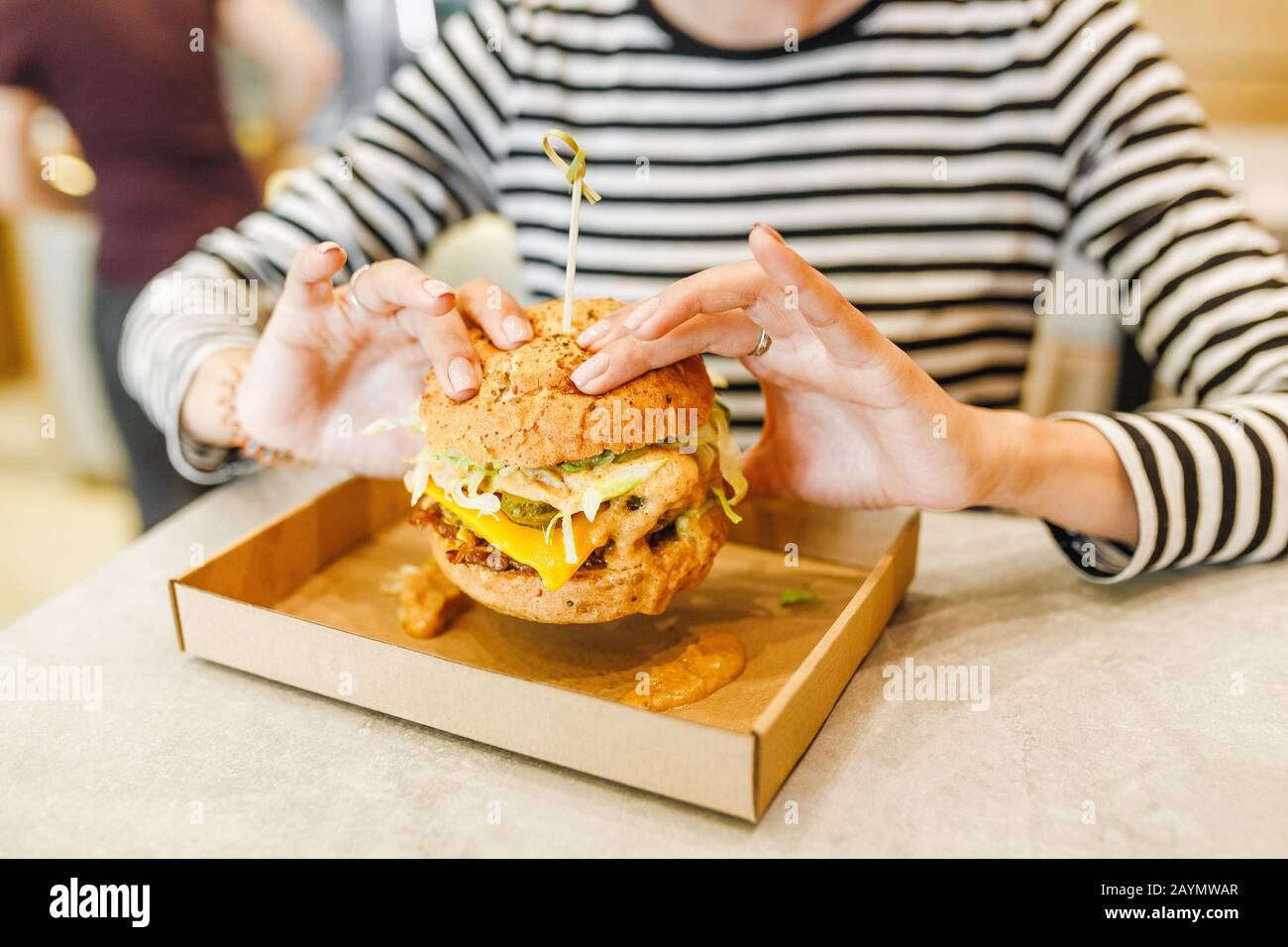 Femme mangeant un hamburger dans un café moderne fastfood, concept de déjeuner Banque D'Images