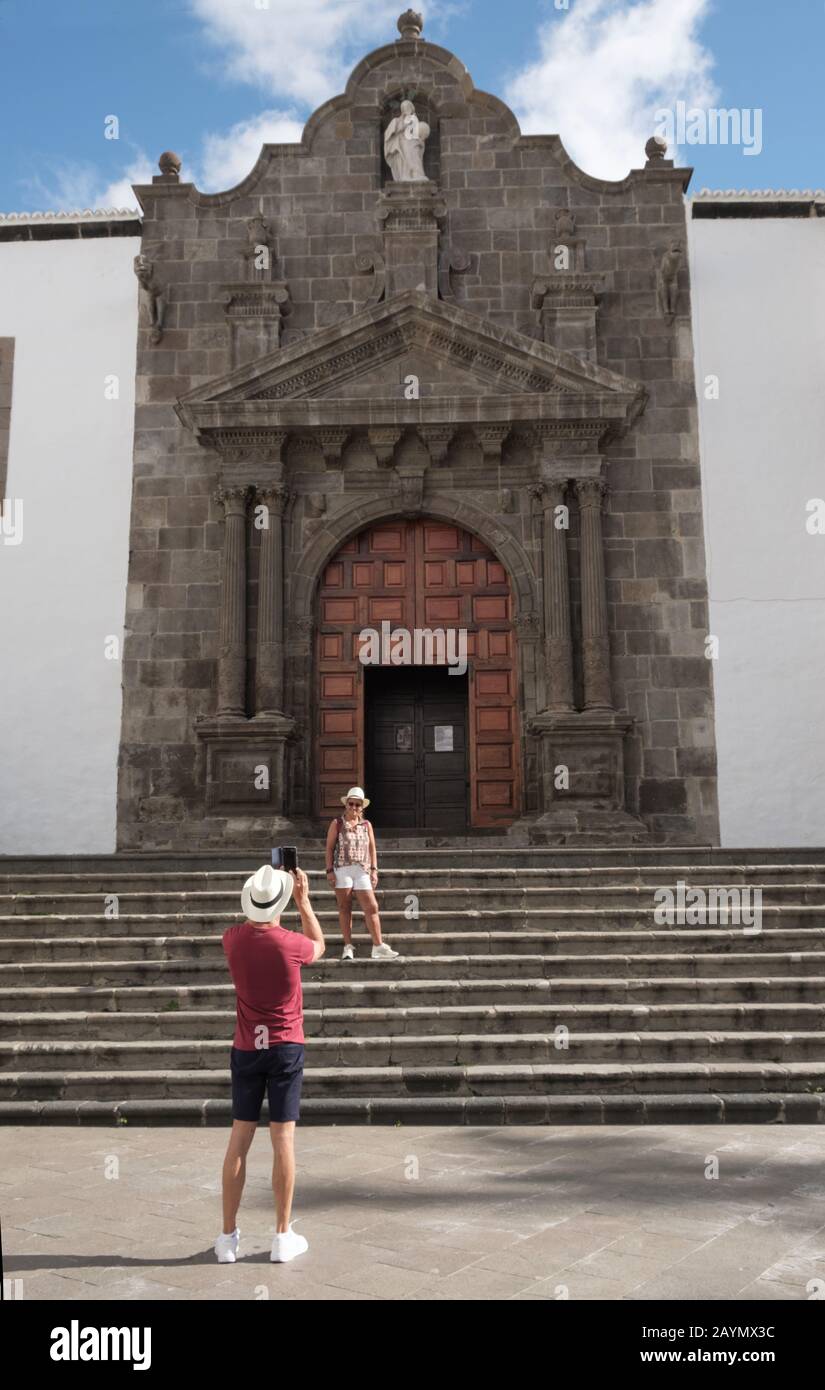 Homme de tourisme en chapeau et short prenant photo de femme au téléphone par grande porte, Plaza San Francisco, Santa Cruz de la Palma, îles Canaries, Espagne Banque D'Images