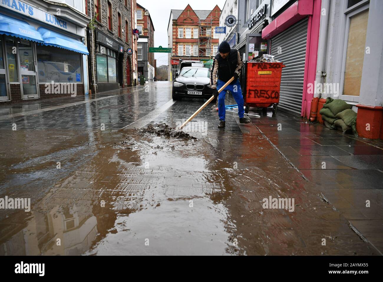 Un homme qui nettoyait la rue à Pontypridd après que Storm Dennis ait frappé le Royaume-Uni, ce qui a conduit à des inondations généralisées. Banque D'Images