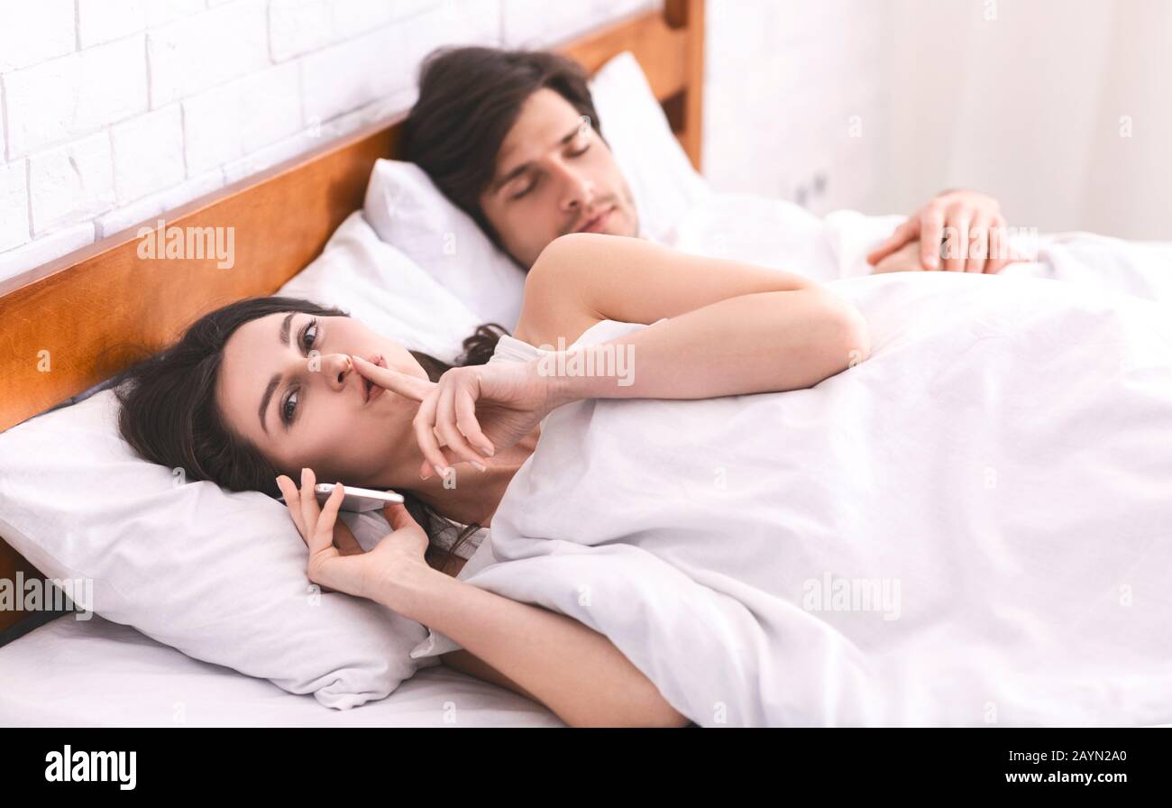 Petite femme qui parle au téléphone dans un lit de famille Banque D'Images