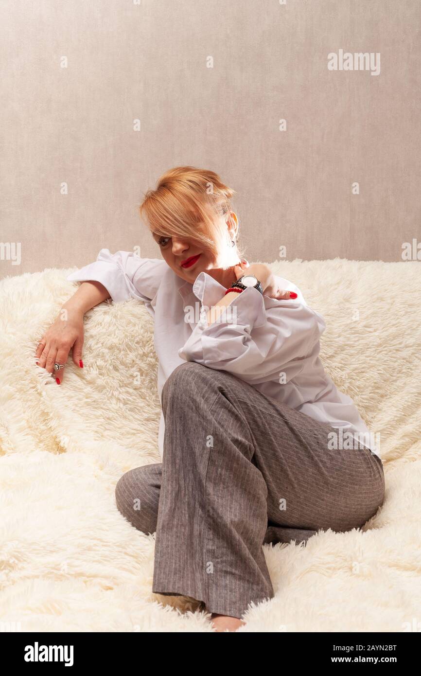 Portrait d'une jolie femme d'âge moyen. Portrait fait maison sur le canapé, blonde d'âge moyen. Banque D'Images