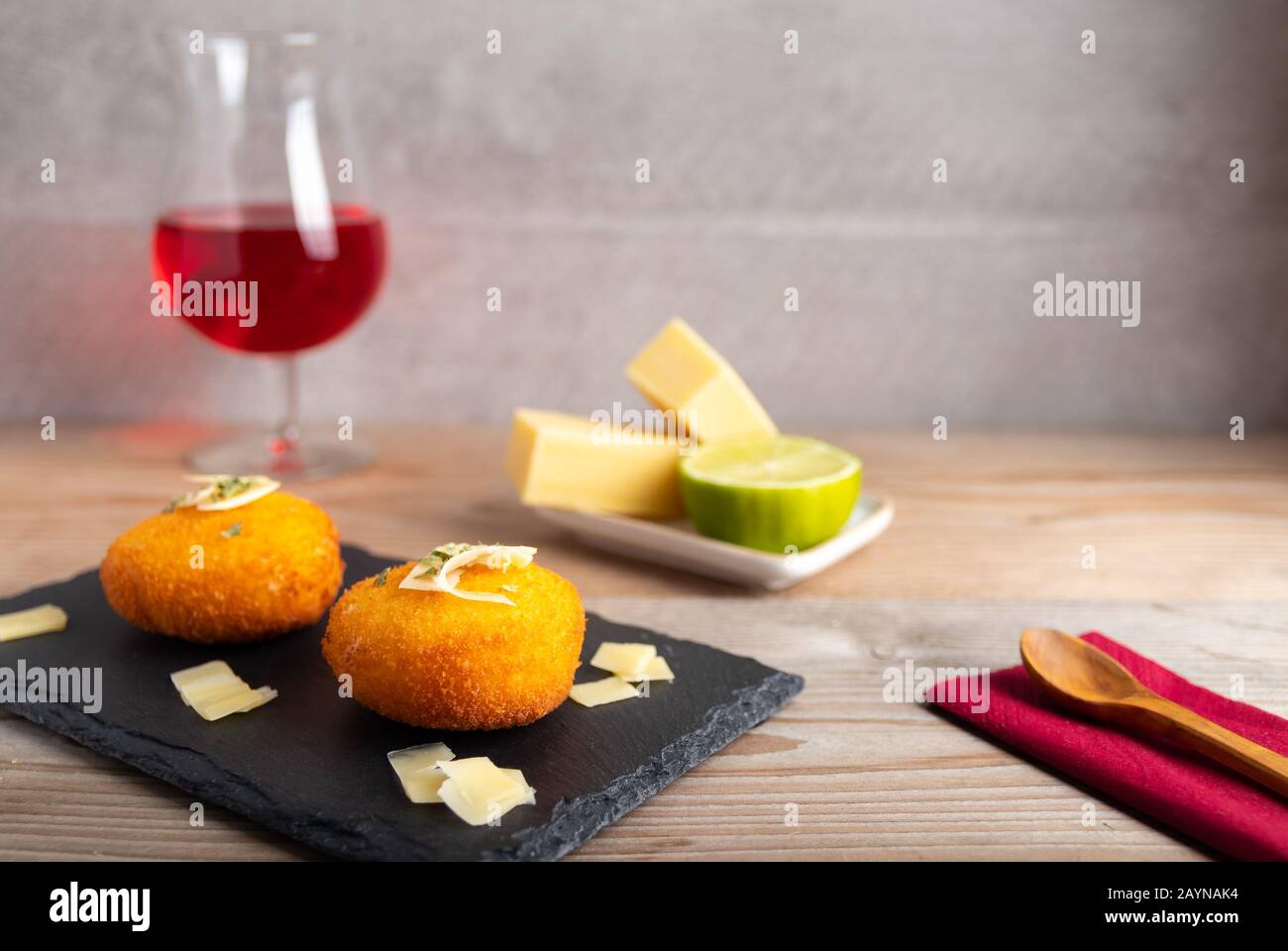 Croquettes maison remplies de fromage avec citron et un verre de vin rouge. Banque D'Images