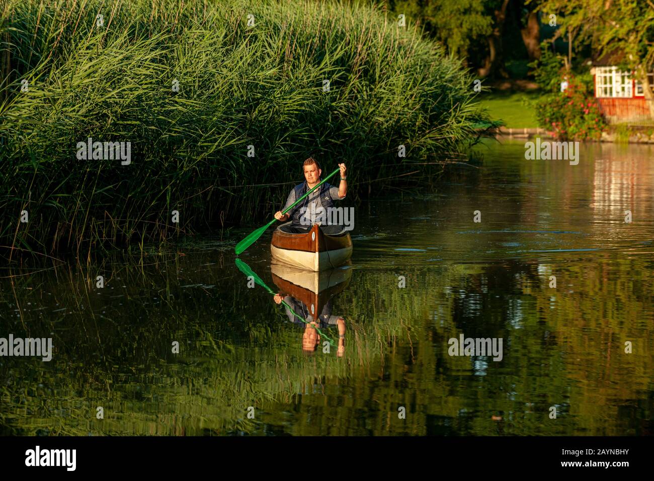 un homme en canoë est en promenade le matin sur une rivière en lumière dorée Banque D'Images