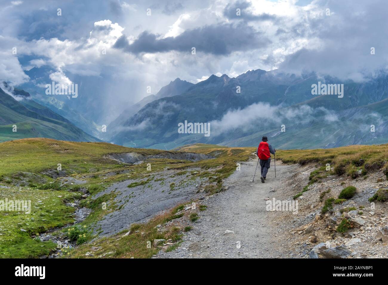 Un hiker solitaire descendant dans une vallée couverte de brume sur le Tour du Mont Blanc Trek dans les Alpes françaises Banque D'Images