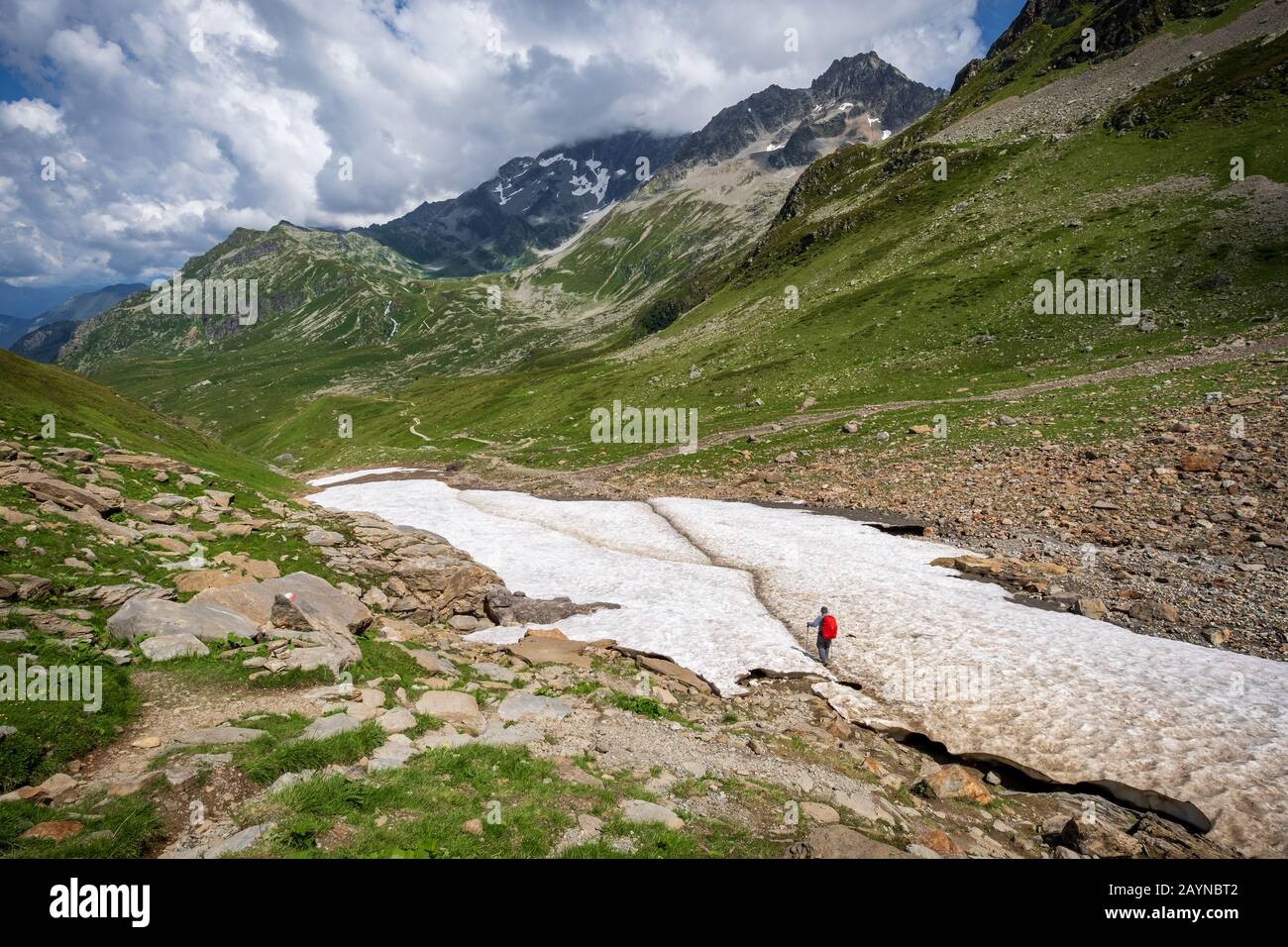 Un randonneur traverse un champ de neige entouré de hauts sommets lors de la randonnée du Mont Blanc dans les Alpes françaises Banque D'Images