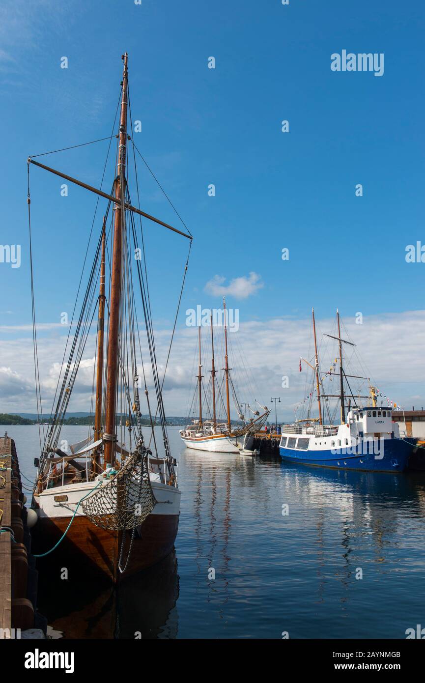 Vue sur les vieux bateaux à voile amarrés dans le port en face de l'hôtel de ville d'Oslo, Norvège. Banque D'Images