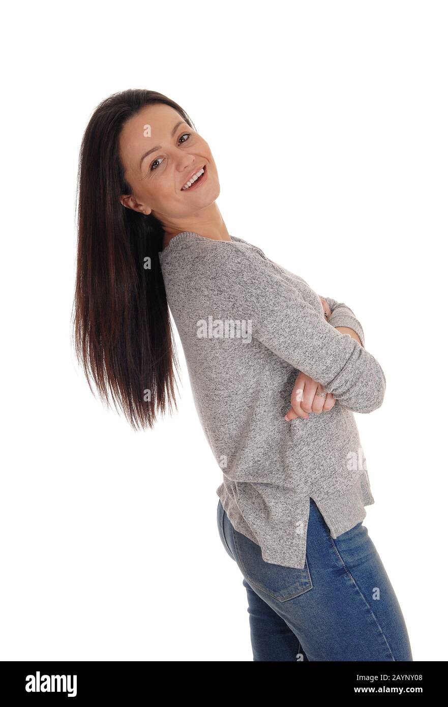 Une jeune femme souriante et charmante se tenant dans le studio se repliant avec ses longs cheveux brunette, isolés pour un fond blanc Banque D'Images
