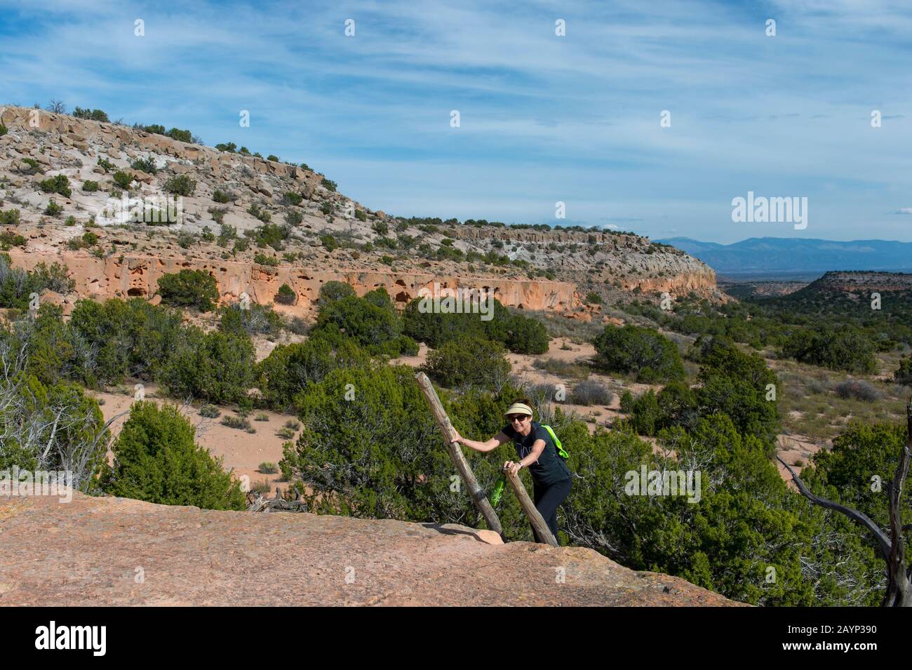 Femme (modèle Release 20020923-10) échelle d'escalade au sommet de la Mesa à Tsankawi, monument national de Bandelier au Nouveau Mexique, aux États-Unis, près de White Rock. Banque D'Images