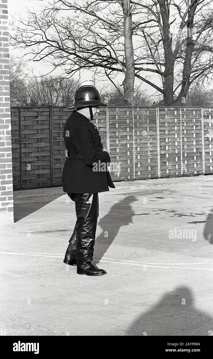 Années 1960, historique, à l'extérieur sur une zone de béton dans une caserne de pompiers, un pompier en uniforme, veste et pantalon et casque de l'époque, participant à un exercice d'entraînement, Fleetwood, Angleterre, Royaume-Uni. Banque D'Images