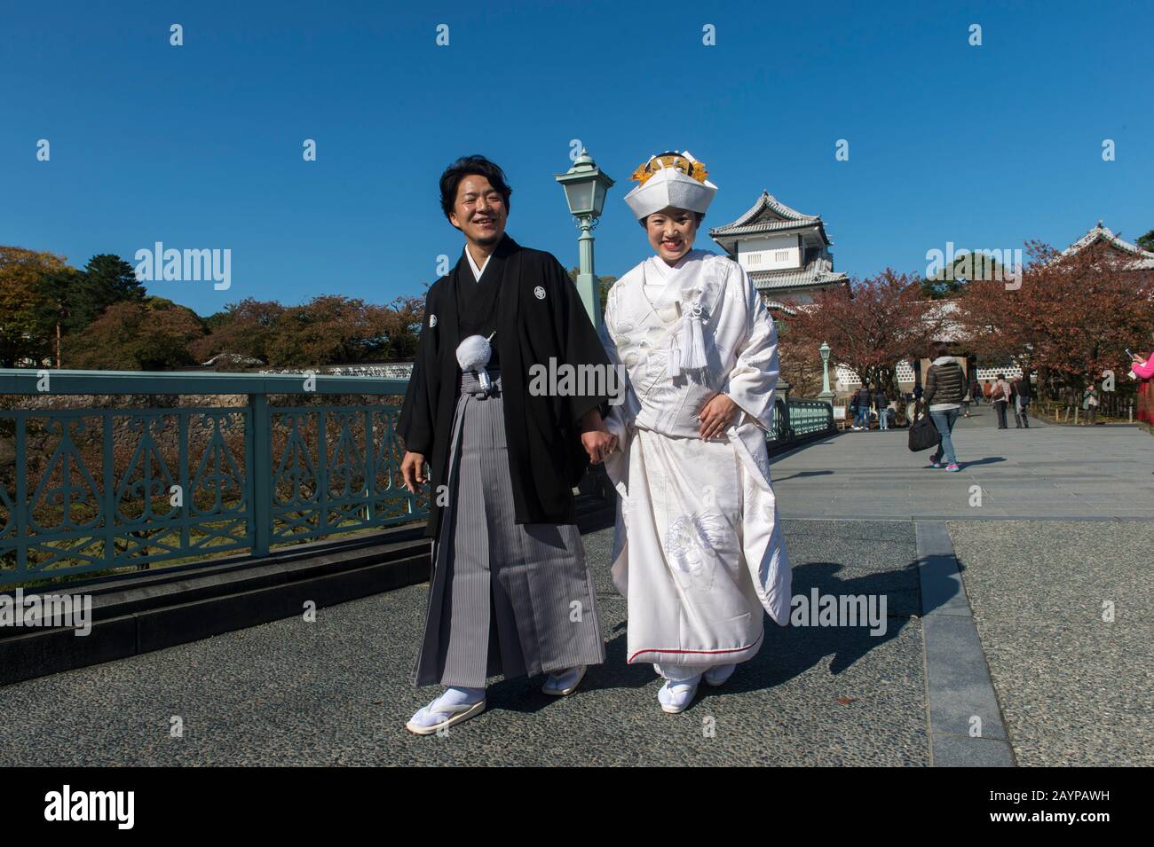 Un couple de mariage dans des vêtements traditionnels se pose devant le château du parc du château de Kanazawa à Kanazawa, préfecture d'Ishikawa, sur l'île d'Honshu Banque D'Images