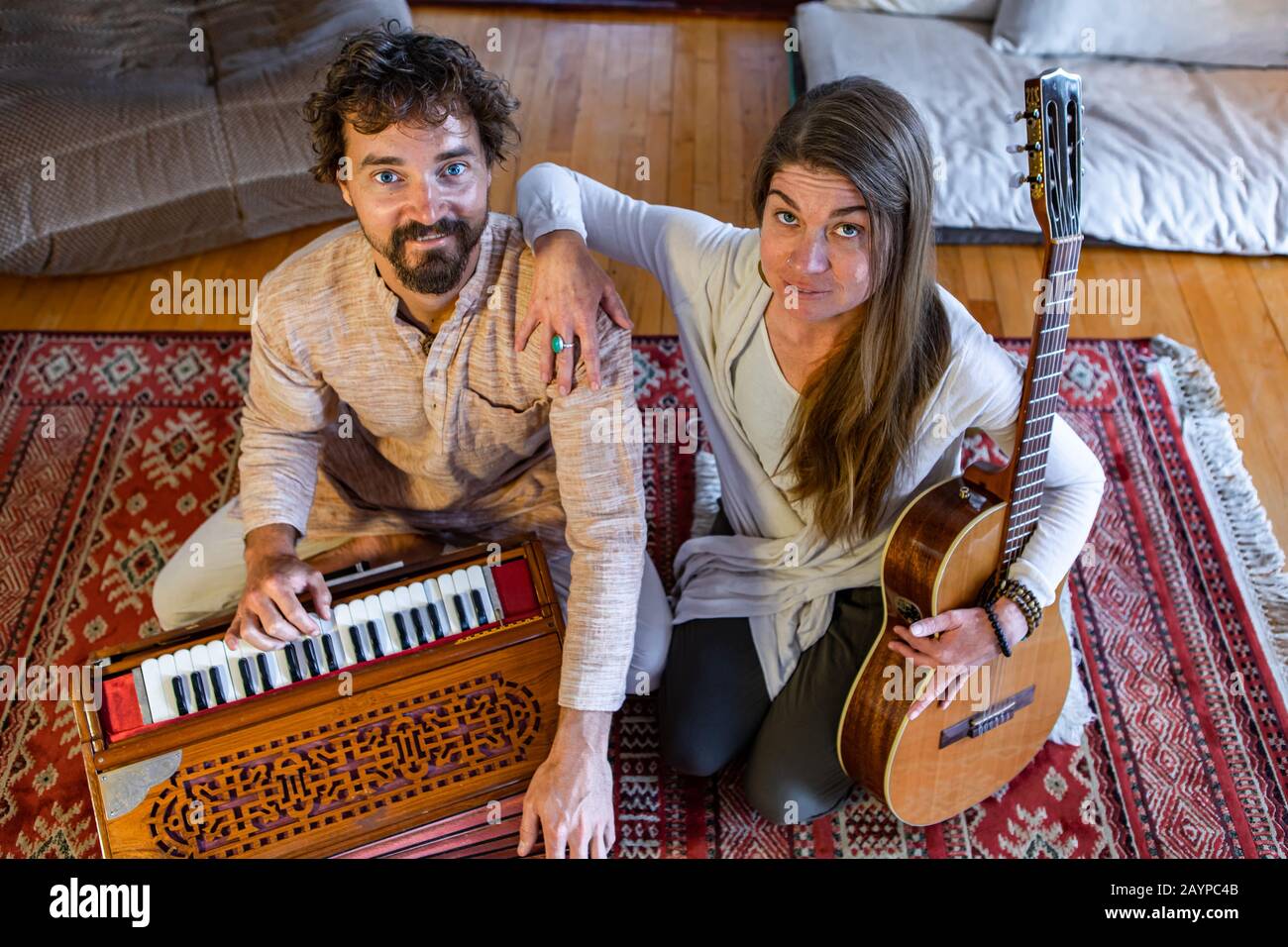 Vue en grand angle de jeunes hommes et femmes chamaniques couple tenant classique et jouant à l'harmonium dans la salle pour la méditation silencieuse Banque D'Images