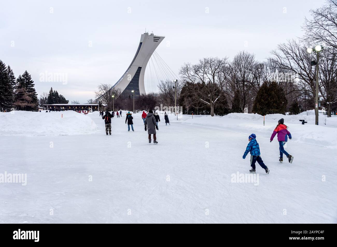 Montréal, CA - 15 février 2020 : patinage sur glace des gens à la patinoire du parc Maisonneuve avec la tour du stade olympique en arrière-plan. Banque D'Images