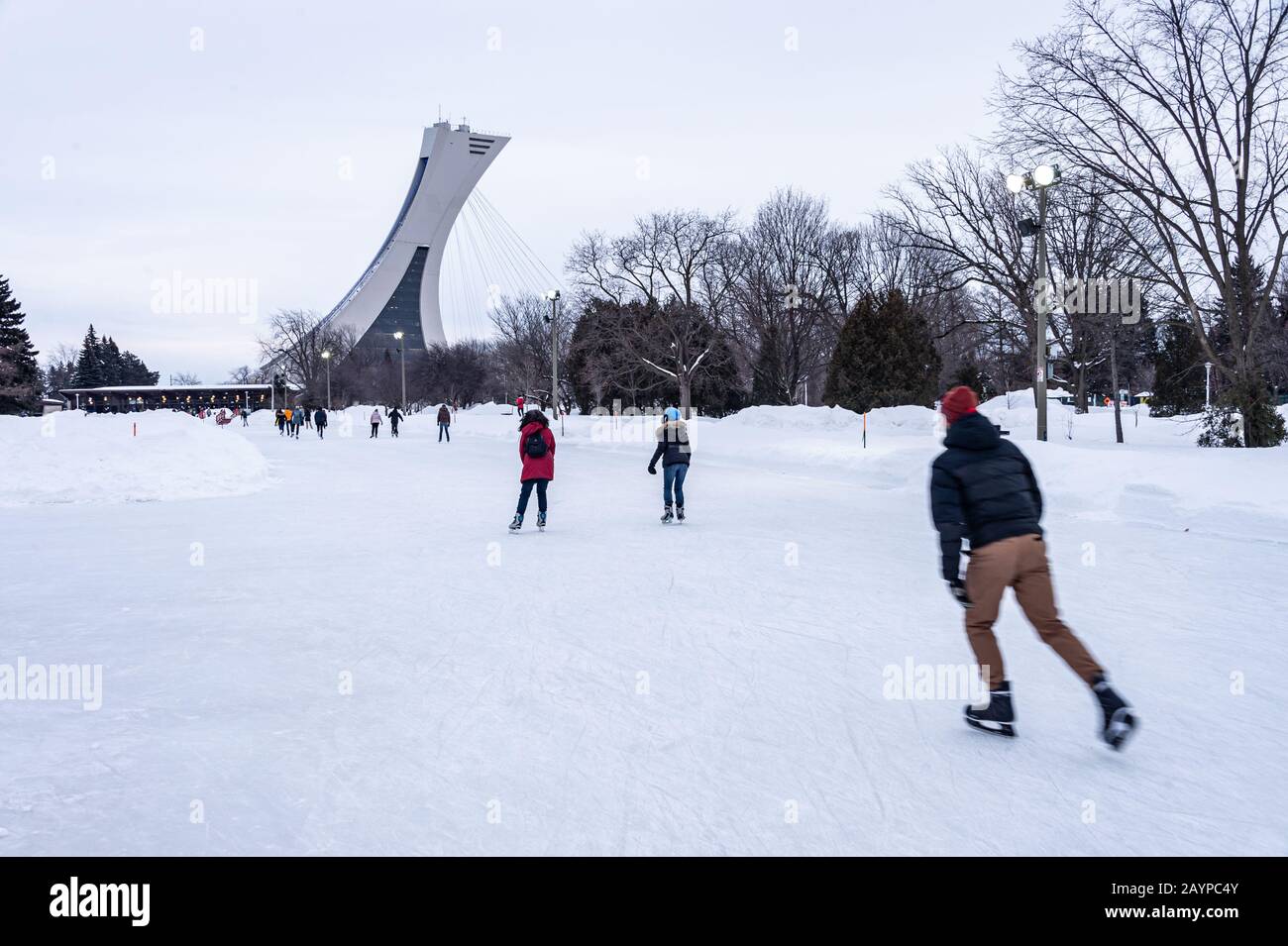Montréal, CA - 15 février 2020 : patinage sur glace des gens à la patinoire du parc Maisonneuve avec la tour du stade olympique en arrière-plan. Banque D'Images