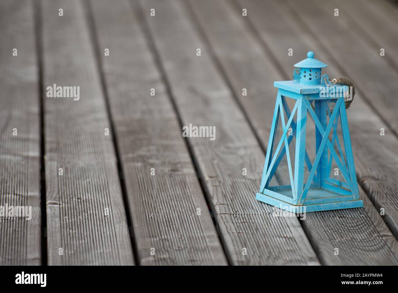 Une lanterne rustique bleu turquoise pâle avec une corde à retenir, exposée sur une terrasse en bois de teakwood Banque D'Images