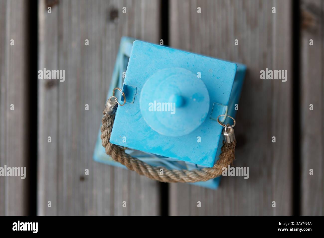 Une lanterne rustique bleu turquoise pâle avec une corde à retenir, exposée sur une terrasse en bois de teakwood Banque D'Images