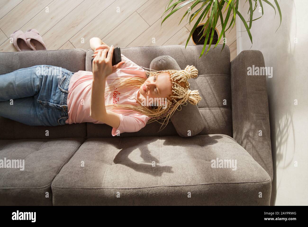 Une femme utilise un smartphone tout en se reposant sur un canapé. Vue de dessus. Banque D'Images