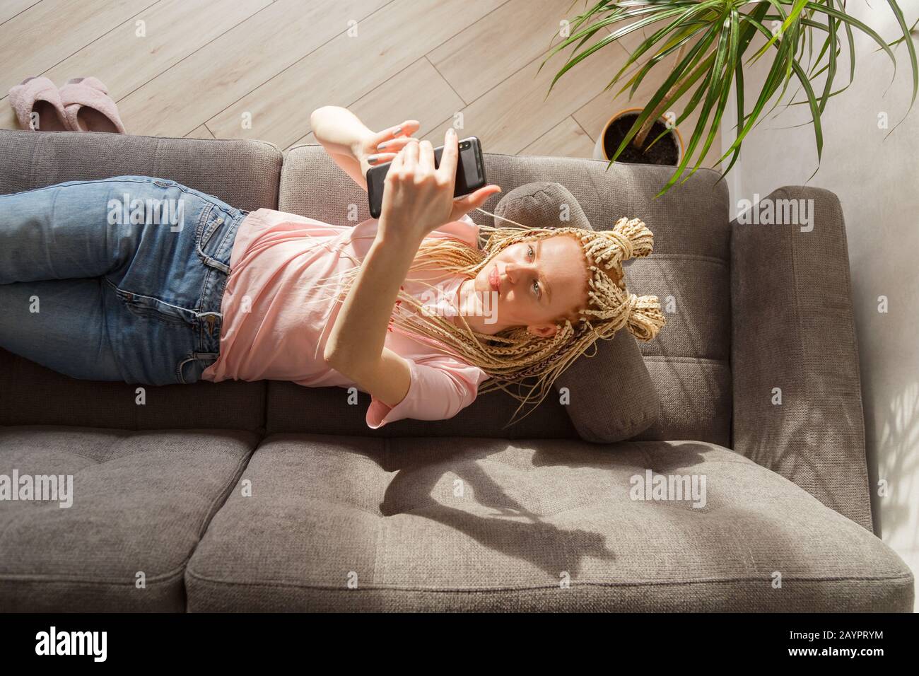 Une femme utilise un smartphone tout en se reposant sur un canapé. Vue de dessus. Banque D'Images