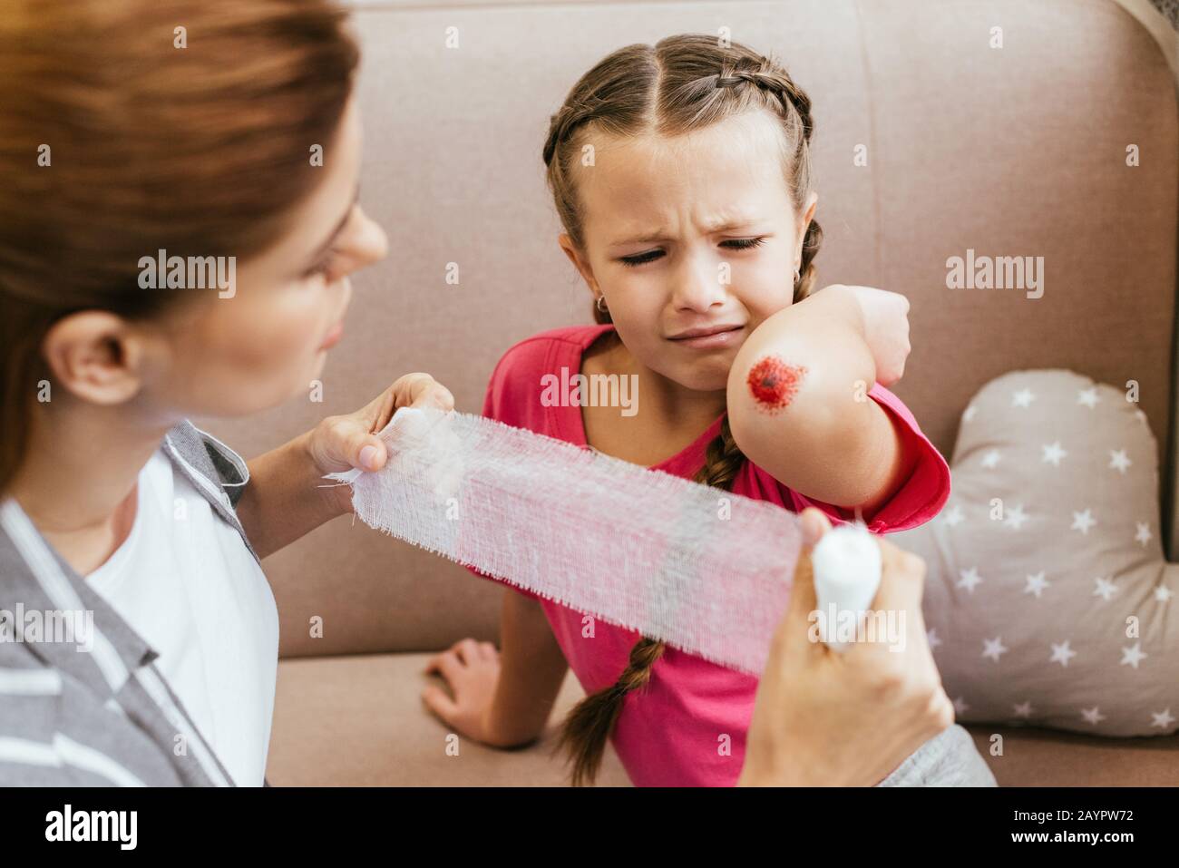 la mère s'inquiétait de bandage autour du coude de la fille pleurant Banque D'Images