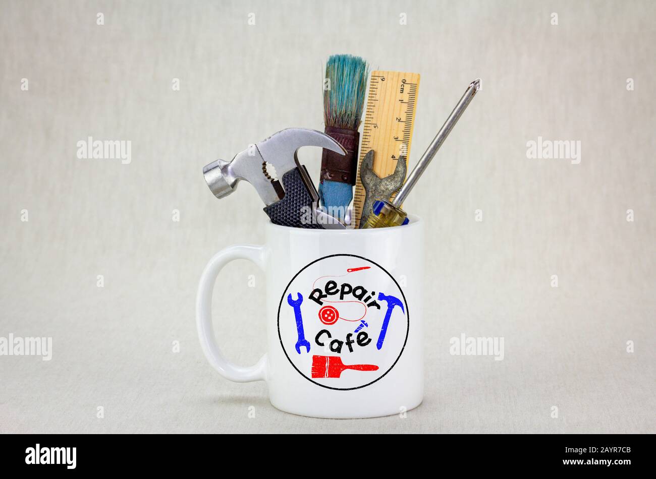 Réparez le logo Cafe sur une tasse sur le plan de table contenant des outils, l'activisme des consommateurs pour réparer les articles ménagers afin de réduire les déchets et de soutenir une vie durable Banque D'Images