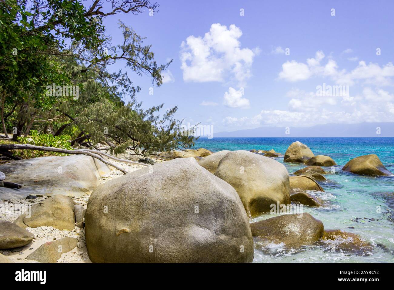 Nudey Beach, Fitzroy Island, les rochers traversent les eaux cristallines de la mer de corail avec la côte du Queensland Australie en arrière-plan. Banque D'Images