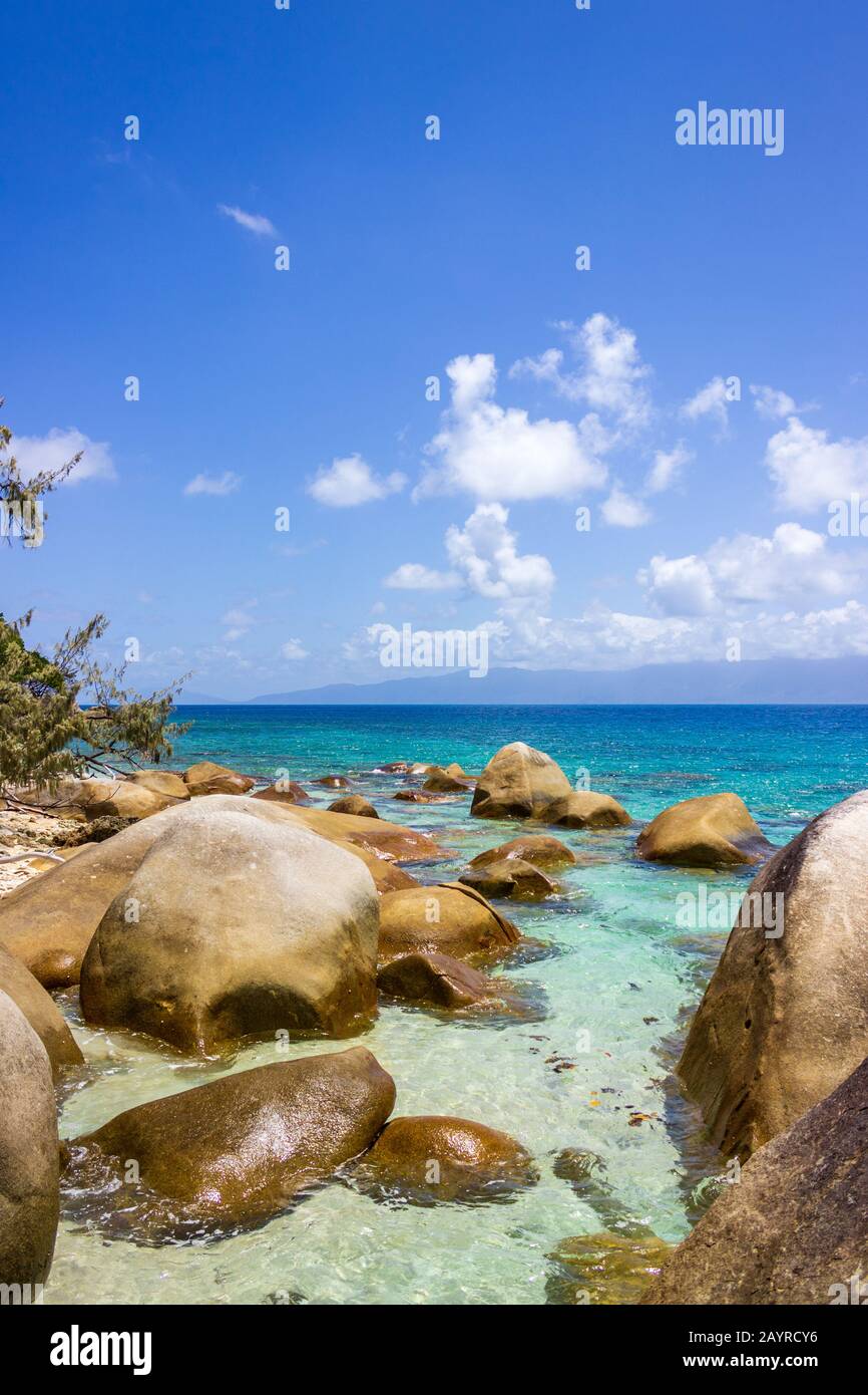 Nudey Beach, Fitzroy Island, les rochers traversent les eaux cristallines de la mer de corail avec la côte du Queensland Australie en arrière-plan. Banque D'Images